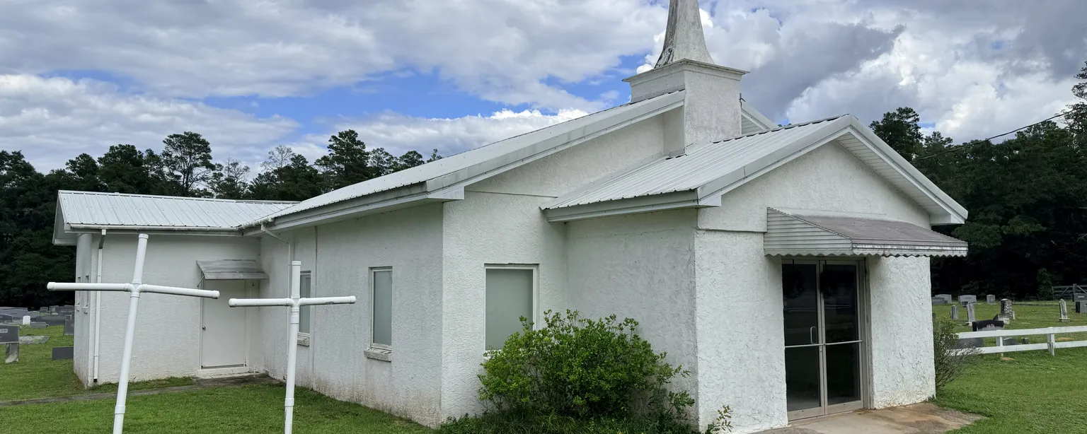 A white country church with a steeple and adjoining cemetery in the New Hope community, Washington County, Florida